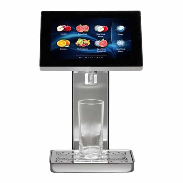 JuiceTouch UC 2 machine with a touchscreen displaying drink options like apple, grapefruit, and water. A glass sits on the metal drip tray below.