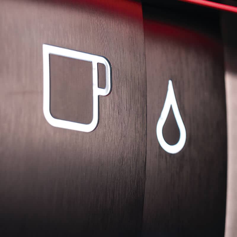 Close-up of a dark wood texture with white icons: a minimalist coffee cup and water droplet symbol