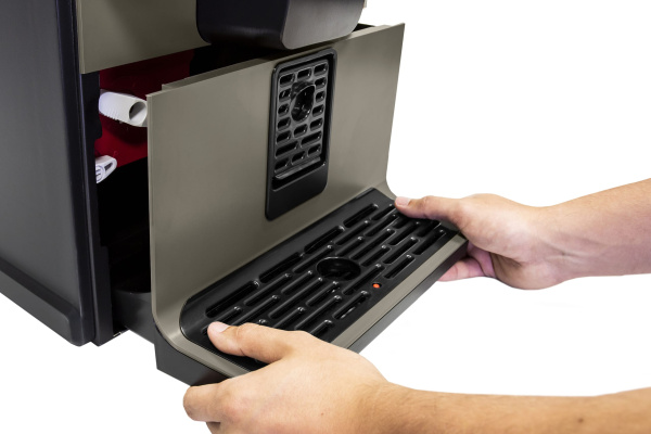 Hands removing a drip tray from under the VITRO X1 AZKOYEN coffee machine.